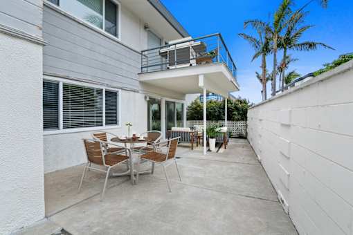 A patio with a table and chairs is surrounded by white walls.