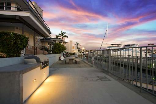A modern building with a rooftop terrace overlooking the ocean at sunset.