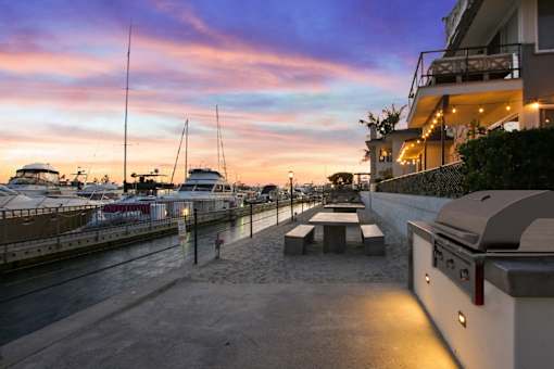 A marina at dusk with boats docked and a building on the right.