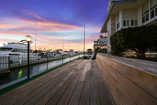 A wooden walkway leads to a building with a boat docked in the background.