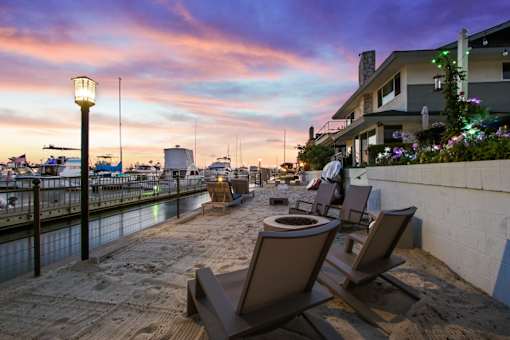 A sunset view of a beachfront with chairs and a table.