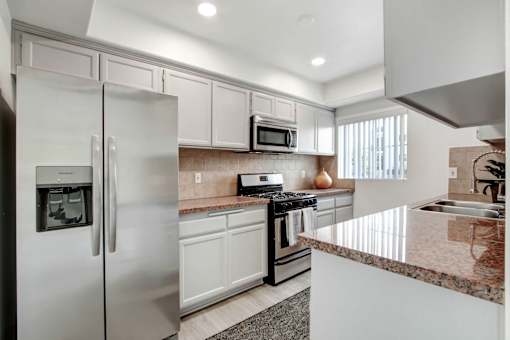 A modern kitchen with a granite countertop and stainless steel appliances.