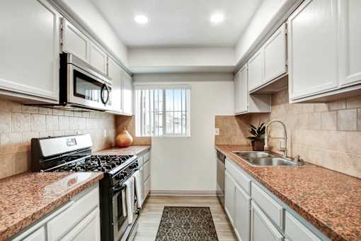 A kitchen with a black stove top oven and a black microwave above it.