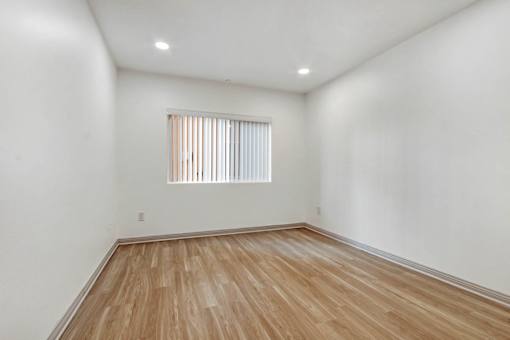 A room with wooden flooring and a window with blinds.