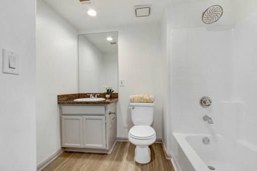 A white toilet sits in a bathroom next to a bathtub.