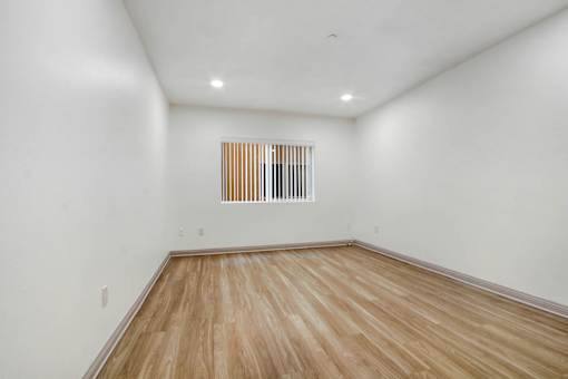 A room with wooden flooring and a window with blinds.