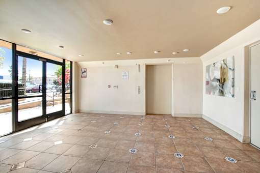 A room with tile flooring and a view of the street through the windows.