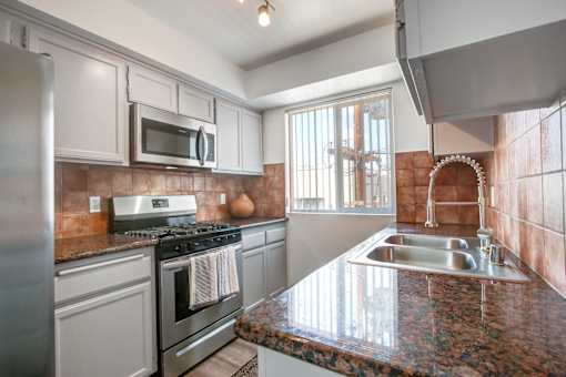 A kitchen with a granite counter top and stainless steel appliances.