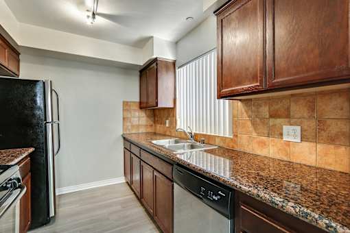A kitchen with brown cabinets and a black refrigerator.
