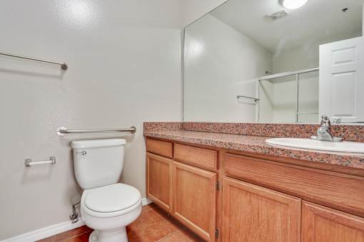 A white toilet sits in a bathroom with wooden cabinets.
