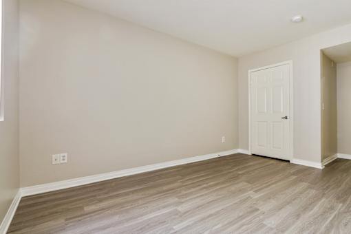 A room with a white door and wooden flooring.