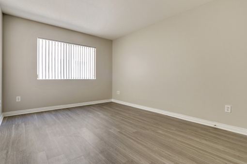 A room with a window and wooden flooring.