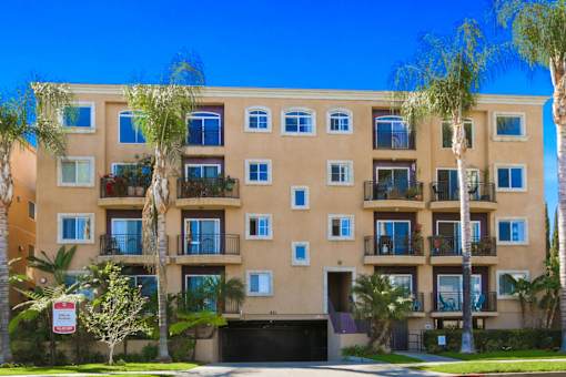 A building with balconies and palm trees in front.