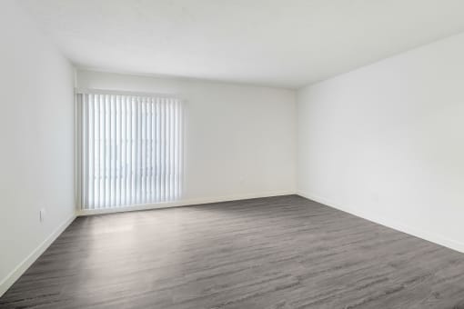 an empty living room with a window and wood floors
