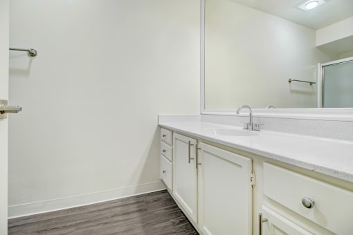 a bathroom with white cabinets and a sink and a mirror