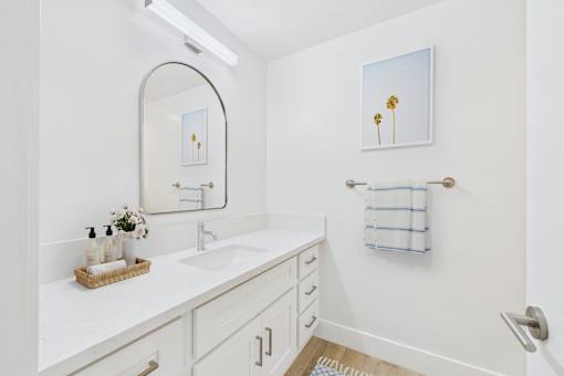 A bathroom with a white counter top and a mirror.