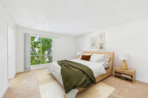 A bedroom with a bed, nightstand, and window.