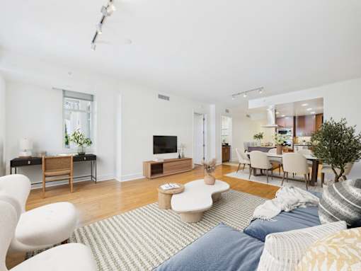 A living room with a white couch and a grey rug.