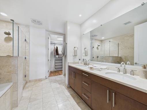 A bathroom with a walk in shower and double sinks.