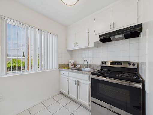 A kitchen with white cabinets and a black stove top oven.