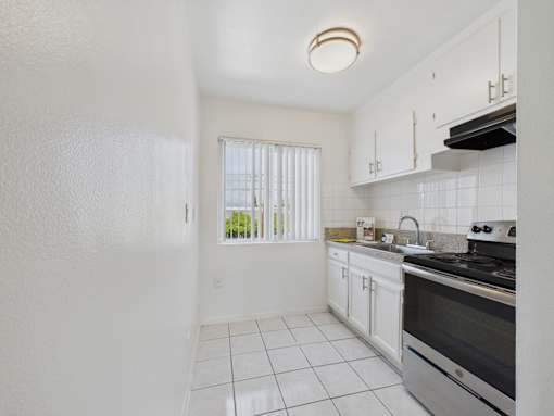 A kitchen with white cabinets and a black stove top oven.