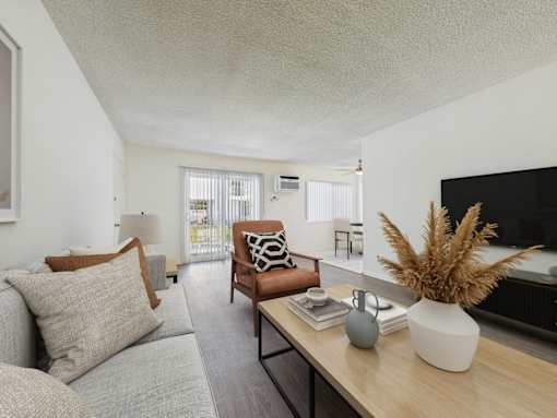 A living room with a grey couch, a brown chair, and a wooden table with a vase on it.