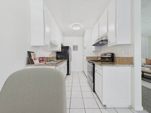 A kitchen with white cabinets and a granite countertop.