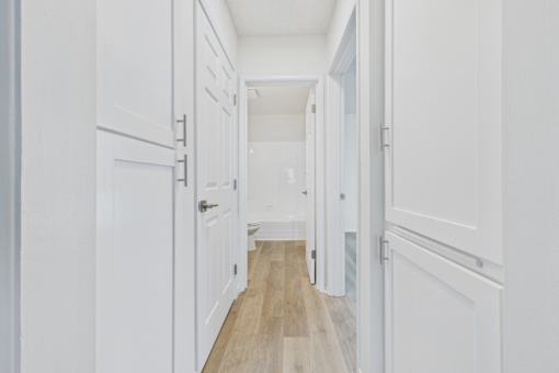 A long hallway with white doors and a wooden floor.