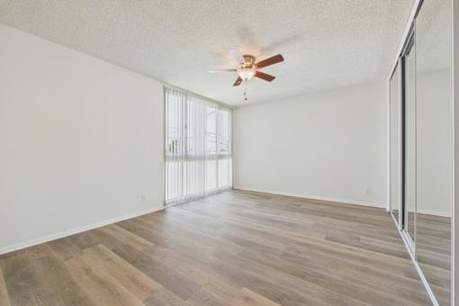 A room with a ceiling fan and wooden flooring.