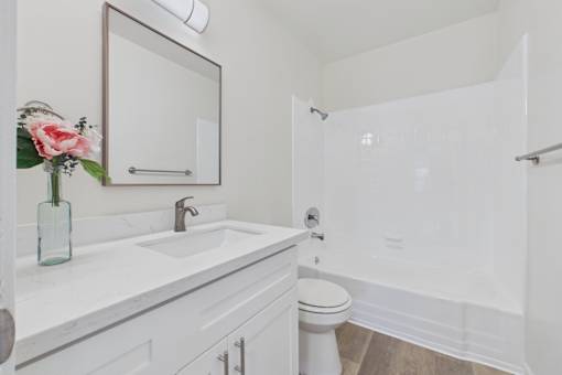 A white bathroom with a sink, toilet, and mirror.