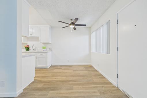 A kitchen with white cabinets and a ceiling fan.