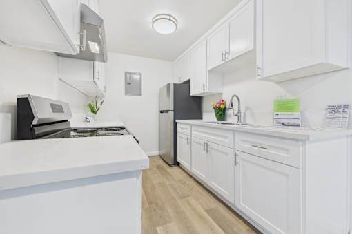 A white kitchen with a black fridge and a white counter.