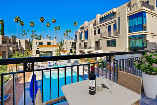 a balcony with a pool and a table with a bottle of wine