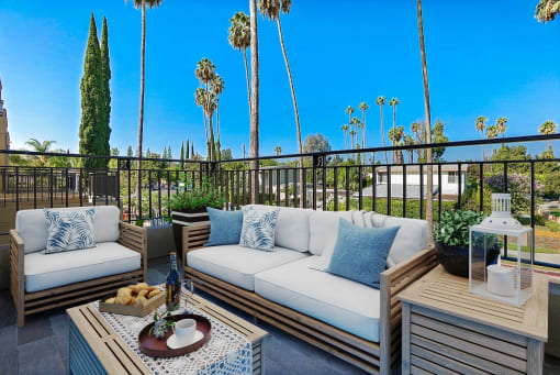 a patio with couches and tables on a balcony with palm trees
