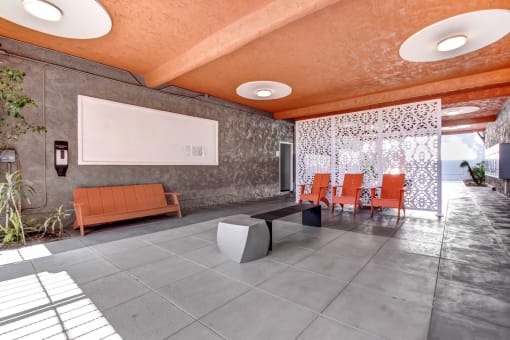 a lounge area with orange chairs and a whiteboard on the wall