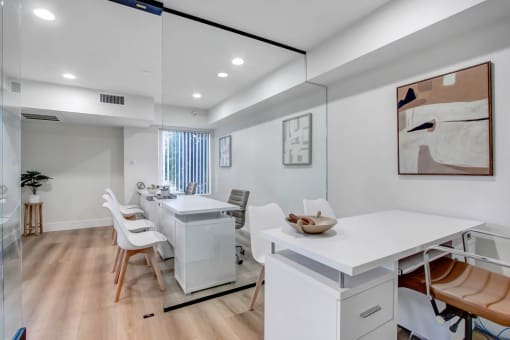a home office with a desk and chairs and a mirror