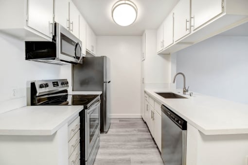 an empty kitchen with white cabinets and stainless steel appliances