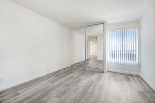 an empty living room with a mirror and a sliding glass door