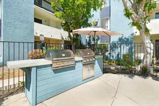 the outdoor kitchen has two grills and an umbrella