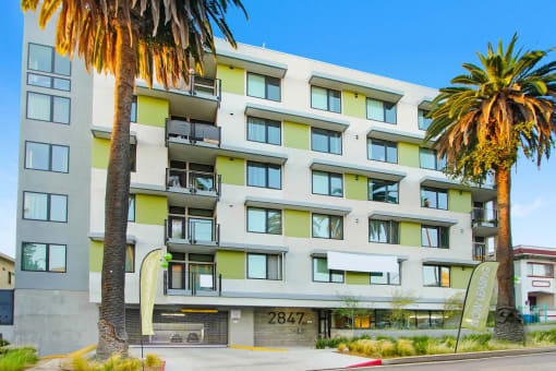 a large apartment building with palm trees in front of it