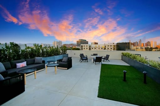 a rooftop patio with a city skyline in the background and grass