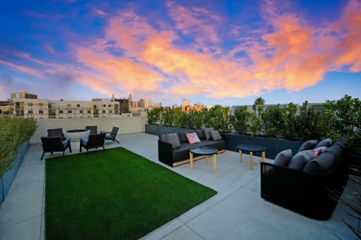 a rooftop patio with couches and tables and grass