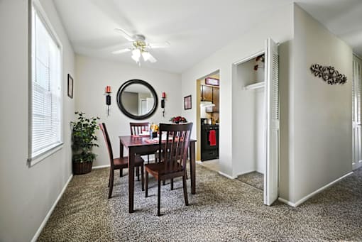 Dining area in a 2-bedroom Ashton Pointe apartment with a carpeted floor and natural light from windows.