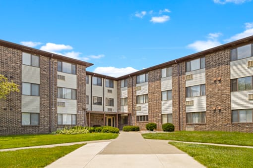 Exterior view of the apartment building at Capri Meadows, featuring side walks and well-maintained landscaping.