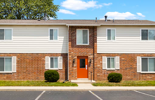 Exterior view of the apartment building at Capri Meadows, showcasing parking spaces and well-maintained landscaping.