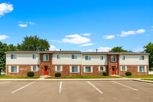 Exterior view of the apartment building at Capri Meadows, showcasing parking spaces and well-maintained landscaping.