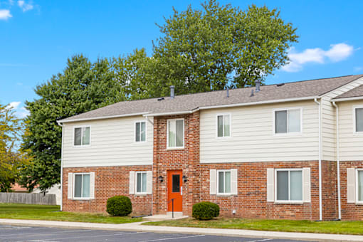 Exterior view of the apartment building at Capri Meadows, showcasing parking spaces and well-maintained landscaping.