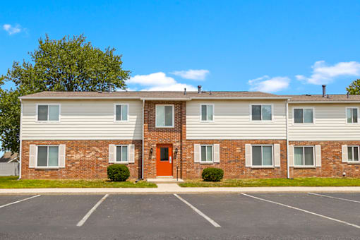 Exterior view of the apartment building at Capri Meadows, showcasing parking spaces and well-maintained landscaping.