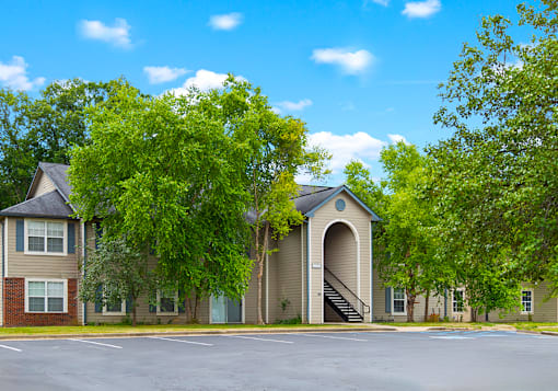 Exterior view of an apartment building with a parking lot in front of it at The Reserve at Chandlers Glen.
