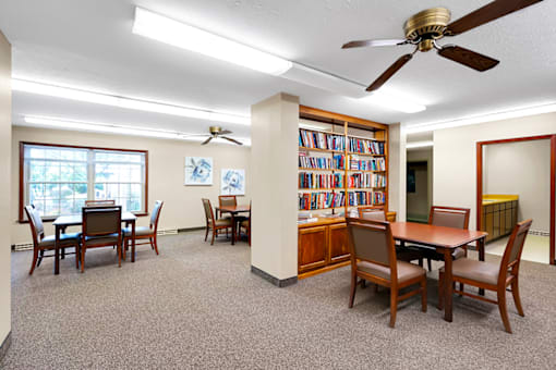 Community room at Fairington of Louisville with comfortable seating and a bookshelf filled with books.